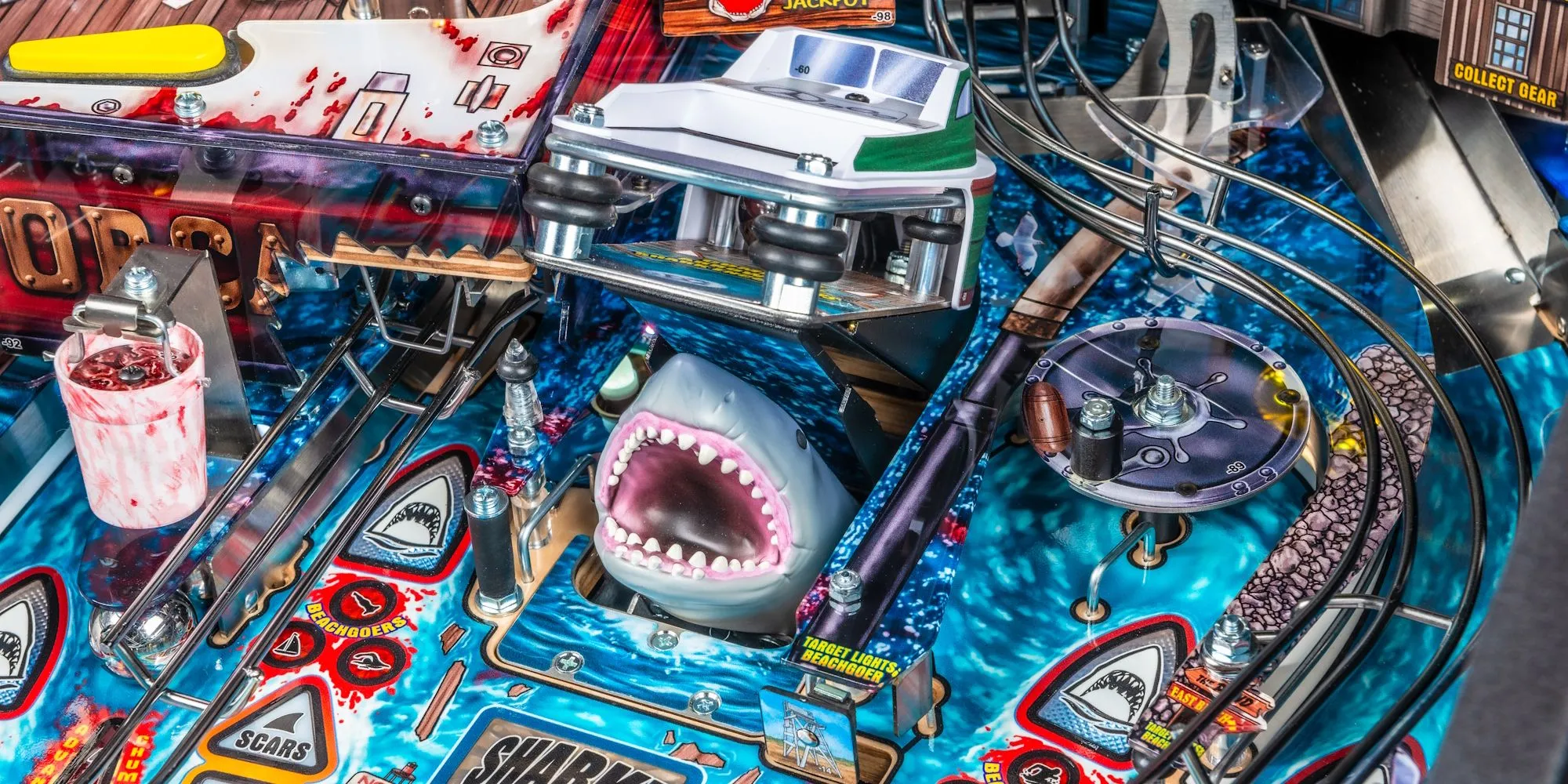 Hình ảnh cận cảnh bàn chơi máy pinball Jaws Stern phiên bản Kỷ niệm 50 năm, hiển thị mô hình thuyền và các chi tiết artwork dưới biển